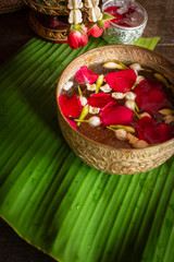 Red rose, Jasmine and popped rice on the calm water surface placed on the wood table Ready for pour water on the hands of revered elders and ask for blessing.