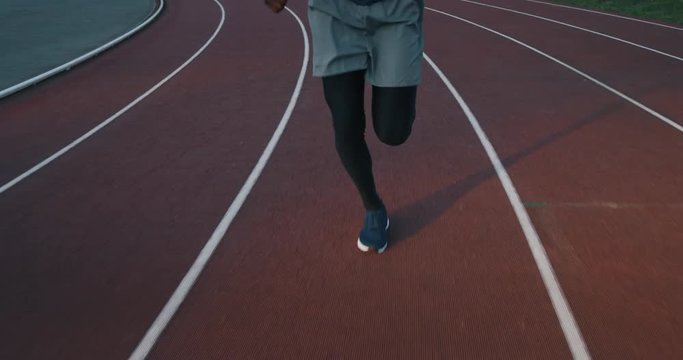 Slow motion of young african male athlete is running on race track in athletics stadium.