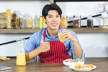 Asian man hold a glass of fresh orange juice..