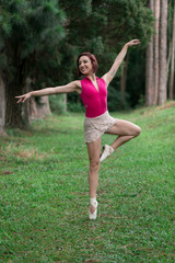 Happy redhead smiling girl dancing in a green park on Brazil in a summer day