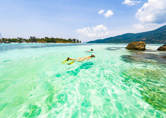 Fototapeta na wymiar couple snorkeling in clear blue sea