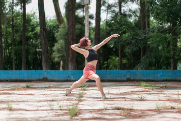 Happy redhead smiling girl dancing in a green park on Brazil in a summer day