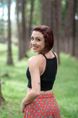 Happy redhead smiling girl dancing in a green park on Brazil in a summer day