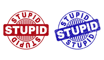 Grunge STUPID round stamp seals isolated on a white background. Round seals with distress texture in red and blue colors. Vector rubber overlay of STUPID label inside circle form with stripes.