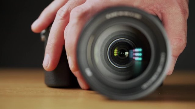A caucasian man's hand zooming the camera lens in on wooden table
