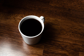 Black coffee in white cups by hand on wooden floors and coffee beans
