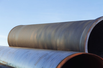 Large diameter metal pipes for water supply lie on storage areas under a open sky