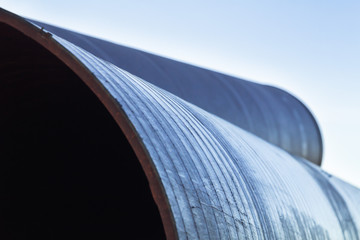 Large diameter metal pipes for water supply lie on storage areas under a open sky