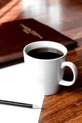 Black coffee in white cups by hand on wooden floors and coffee beans