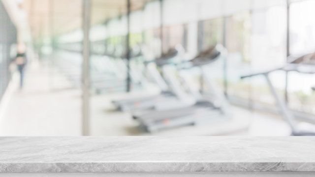 Empty white marble stone table top on blurred with bokeh Exercise room,fitnees and gym interior background - can be used for display or montage your products