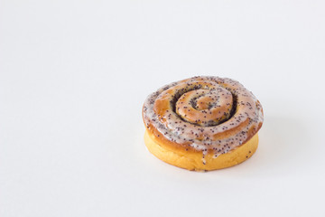 fresh baked yellow brown bun with cream and poppy seeds close-up with shadows on a white background