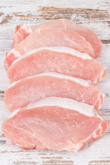 Slices of fresh loin for cooking on rustic board