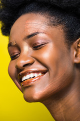Fototapeta premium Happy laughing african american woman with closed eyes isolated on yellow