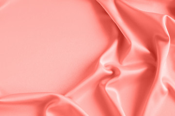 Close up of ripples on silk fabric. Satin textile background. Pink Coral color.