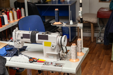 White electric industrial sewing machine in a workshop for sewing and working with fabrics.