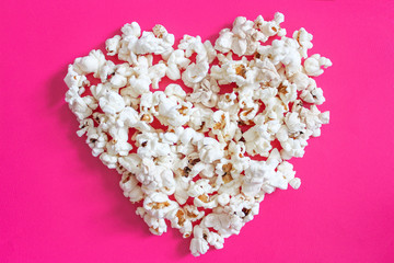 Tasty salted popcorn  on pink background. Flat lay of pop corn. Top view. Food, snack concept. Cinema snack. 