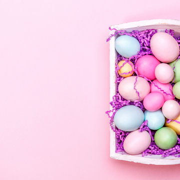 Multicolor eggs in a white tray. Creative Easter concept. Modern solid pink background. Square