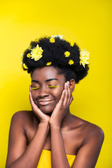 Relaxed african american girl with chrysanthemums in hair with closed eyes isolated on yellow