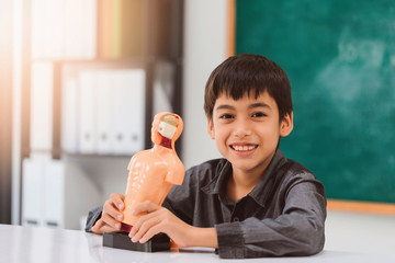 Asian happy school boy learning and play with Body organs model on black board background with copy space.Creative education of kid student concept.