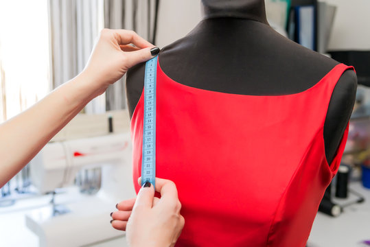 dressmaker designer working with mannequin in dress with equipment. take measurements