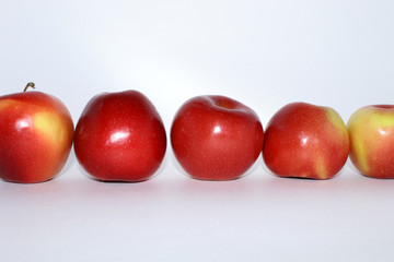 Five red apples in a row horizontally on a white background