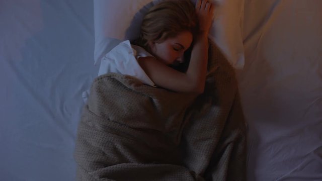 Female tossing and turning in bed, cant falling asleep because of noise outside