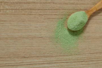 Obraz na płótnie Canvas Wooden spoon with powdered matcha green tea