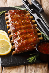 Delicious spicy grilled pork ribs with chilli sauce and lemon closeup on a slate board. vertical