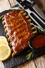 Grilled pork ribs served with chilli sauce and lemon closeup on a slate. vertical