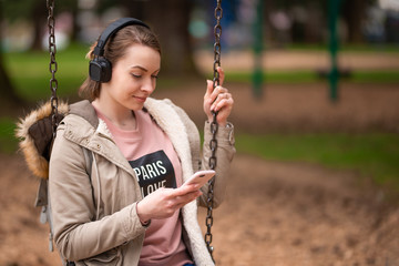 listening to music . young energetic girl on a swing listening to music