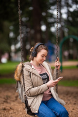 listening to music . young energetic girl on a swing listening to music