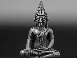 Indoor black and white photography of a small buddha statue.