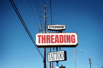 Obraz premium aged eyebrow threading and tattoo sign