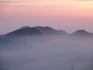 Sun set in Taiwans mountain region - Alishan mountain sun set in warm pastel colors with fog between mountain ranges