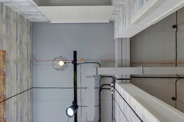 wires, ventilation and lamp on grey ceiling