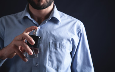 Man spraying perfume on his neck.