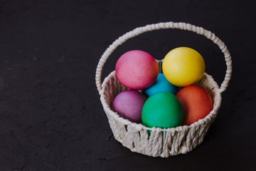 Colored easter eggs in a basket on a black background