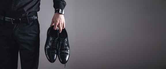 Man holding black shoes. Fashion concept - obrazy, fototapety, plakaty