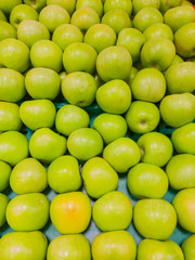 Many beautiful green apples in a box in a supermarket.