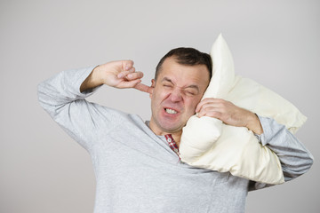 Sleepy man with pillow closing his ear