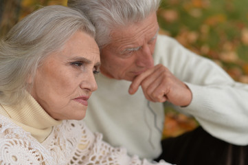 Close up portrait of sad senior couple in autumn park