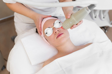 Obraz na płótnie Canvas Professional cosmetologist is making cavitation rejuvenation skin treatment. Young woman is lying and relaxing. Radio wave lifting