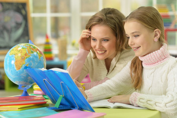 Cute girl with her mother doing homework