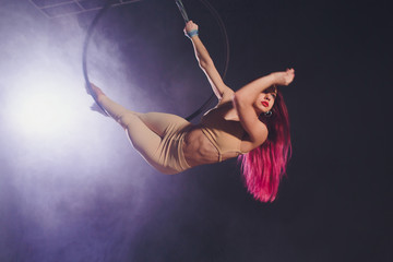 Aerial acrobat in the ring. A young girl performs the acrobatic elements in the air ring.