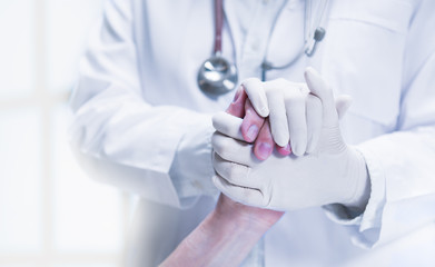 Medical doctor wearing latex gloves holding patient’s hand to give support in hospital setting