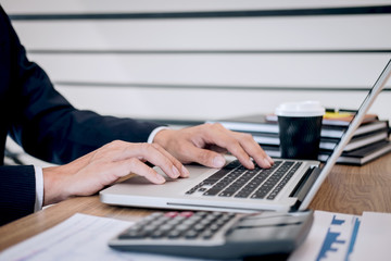 Businessman accountant working new project on laptop computer with report document and analyze document graph and diagram, doing finance making notes statistics