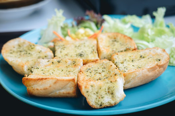 Garlic bread on the blue dish and vegetable salad