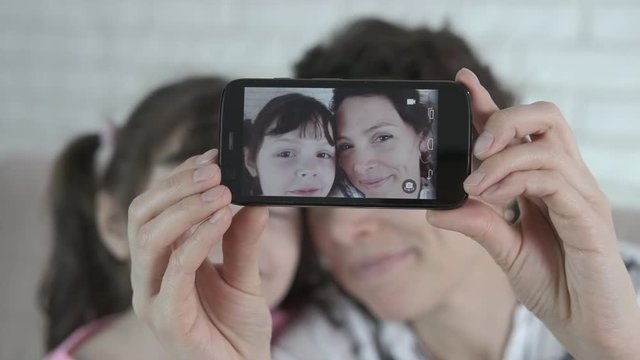 Photos on the smartphone. Mother and daughter are photographed on a smartphone.