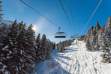 Fototapeta na wymiar Traveling up an alpine mountainside on ski chair lift