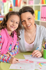 Close up portrait of mother with daughter drawing with colorful pencils